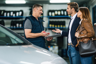 happy-auto-repairman-communicating-with-young-couple-workshop.jpg